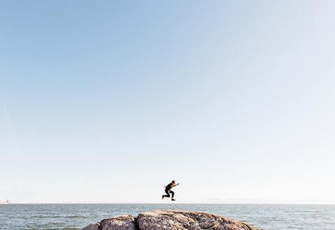 Guy jumping no rock at beach